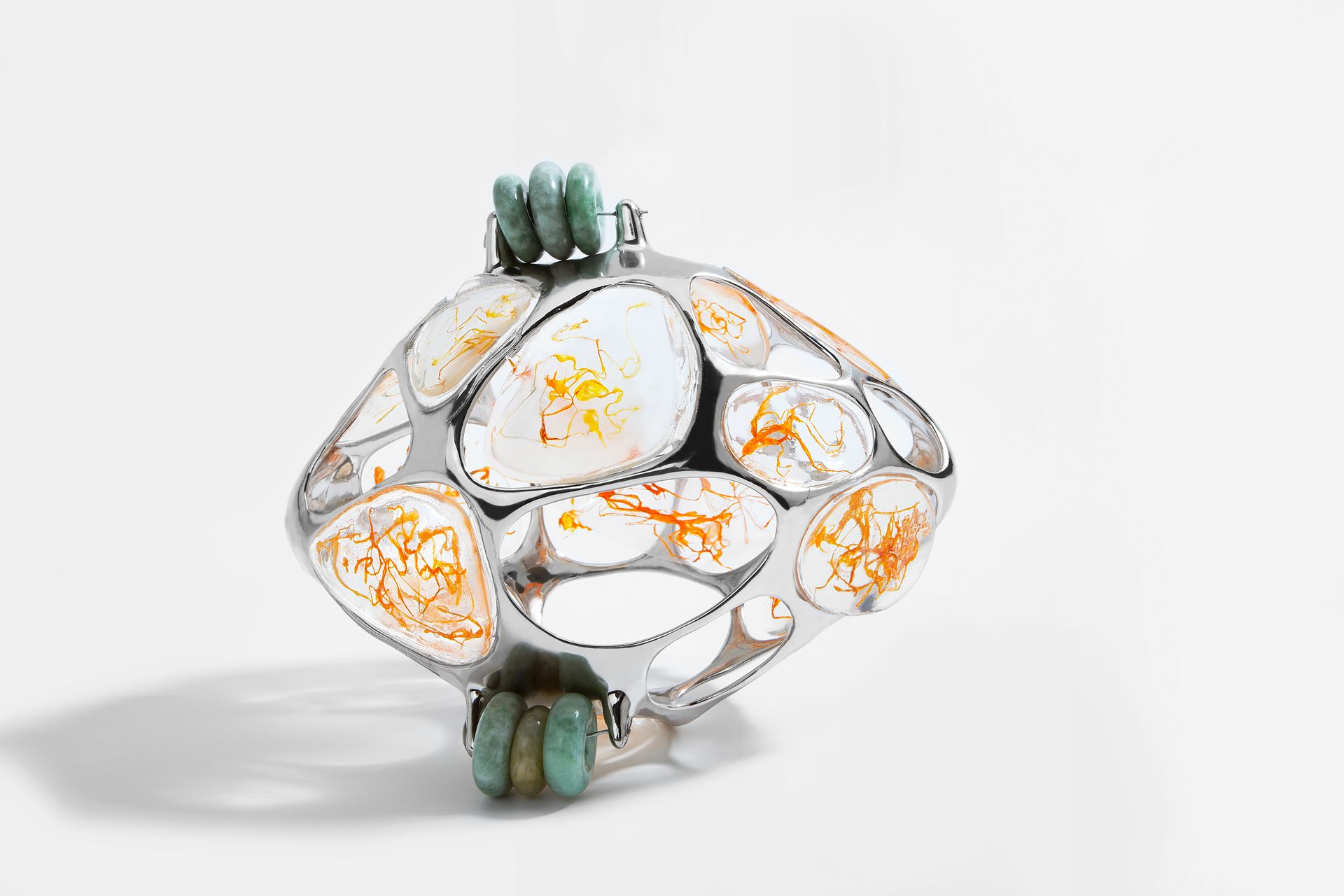 The back ornament as an object: a cage of metal cells holding translucent membranes, with green jade beads at both ends.
