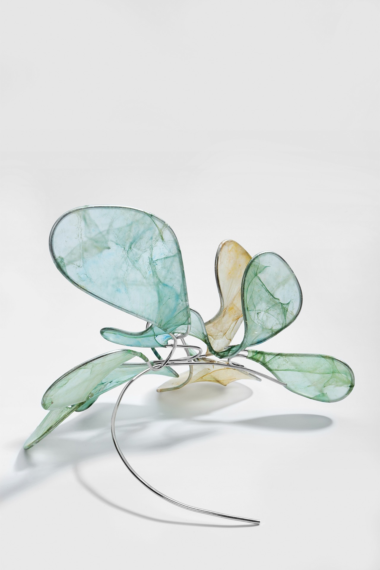Petal-like organic membranes opening above a curved metal structure.